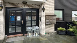 A building with a black double door, a small awning, and a mailbox. - Margeritenhaus - Relaxed island life: Cozy vacation apartment in Westerland (Sylt)