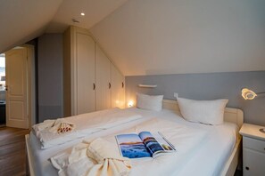 Une chambre à coucher comprenant un lit, des tables de chevet, une lampe de chevet, une armoire et une lampe de lecture.