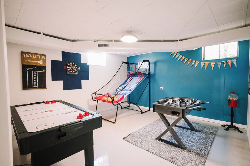 Una habitación con mesa de futbolín, dardos y un mini trampolín.