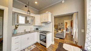 A modern kitchen with white cabinetry, a built-in microwave, and a stove. There is a dining area with a wooden table and chairs. - Historic Downtown Hawley Loft (Hawley)