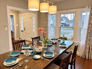 A dining room with a wooden table set for four, blue and white dinnerware, and a vase with flowers.