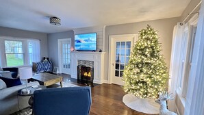 Un salon avec une cheminée, un téléviseur, un sapin de Noël et une décoration représentant un cerf.