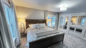Une chambre à coucher avec un grand lit, une table de chevet, une lampe et une armoire avec des miroirs.