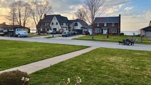 Une rue résidentielle bordée de maisons, avec des voitures garées et un ciel dégagé.