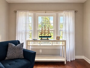 A room with a blue sofa, a white console table, and a model ship. - The Blue House with Lake Views (Erie)