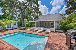 A pool area with a brick deck, lounge chairs, and a barbecue grill. - Historic 1930s Cottage + Heated Pool + 12mi to beaches & 1 mi to downtown (Palmetto)