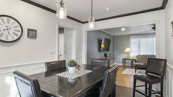 A dining area with a dark wooden table, black leather chairs, and pendant lighting.
