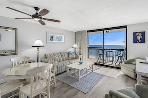 Relax in this stylish living room with a sofa set, dining table, and balcony offering ocean views.