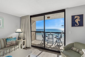 Relax on the deck with ocean views, featuring a striped sofa and a round table.
