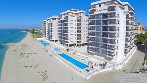 Een strandhotel met meerdere verdiepingen, een zwembad en een strandgedeelte.