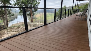 Un pontile in legno con ringhiera metallica che si affaccia su un fiume e sulla vegetazione.