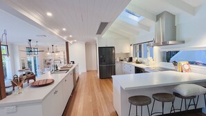 A modern kitchen with a central island, bar stools, and a large window.