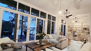 A spacious living room with a large sectional sofa, a coffee table, and a dining area with a chandelier.