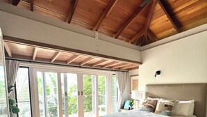 A spacious bedroom with a large bed, wooden flooring, and a sloped ceiling.