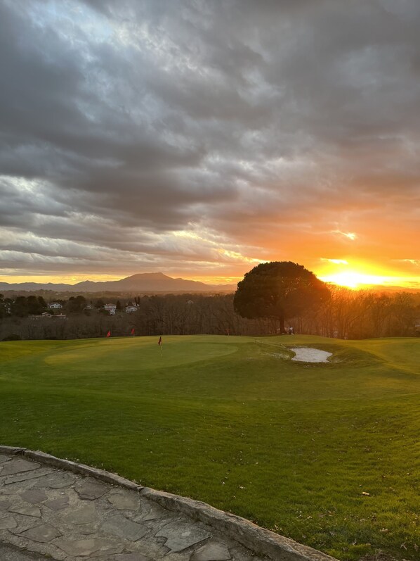 A golf course with a clear sky and a sunset.
