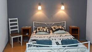 A bedroom with a bed, two bedside tables, a chair, and a wall-mounted lamp.