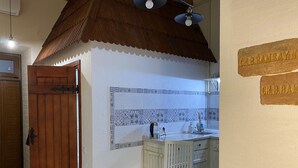 Una cocina con salpicadero de azulejos, armarios de madera, un lavabo y una mesa de comedor.
