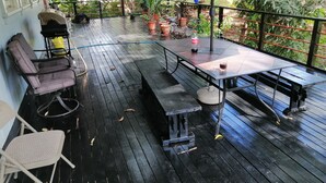 A covered outdoor patio with a wooden deck, a table with chairs, and potted plants. - Remodeled house in Gamboa. Next to the Panama Canal, nature and tranquility. (Gamboa)