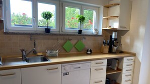 Eine Küche mit Spüle, Geschirrspüler, Schränken und einem Fenster mit Pflanzen.