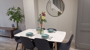 Un espace repas avec une table en marbre blanc, des assiettes de couleur turquoise et des chaises noires.