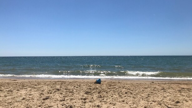 Une plage avec un ciel dégagé et une mer calme.
