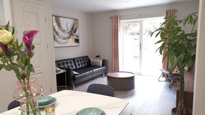 Un salon moderne avec un canapé en cuir noir, une table à manger avec des assiettes vertes et un grand tableau abstrait accroché au mur.