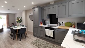 Une cuisine moderne avec des meubles gris, un four noir et une table à manger en bois, assortie de chaises.