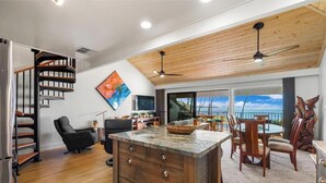 A modern kitchen with a wooden ceiling, a dining area with a view, and a spiral staircase. - Ma'alaea Surf #C-7 – Oceanfront Getaway with Spectacular Views & Pool (Kihei, Maui)