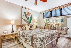 A spacious bedroom with a large bed, a bedside table, a nightstand, a mirror, and a ceiling fan.