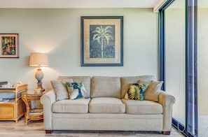 A living room with a beige sofa, a small side table with a lamp, and a framed picture on the wall.