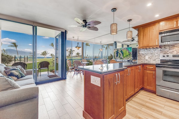 A modern kitchen with wooden cabinets, a large island, and a view of the outdoors.