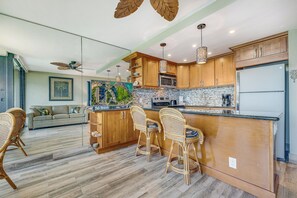 Una cocina moderna con armarios de madera, una isla central con taburetes altos, un microondas y un refrigerador.