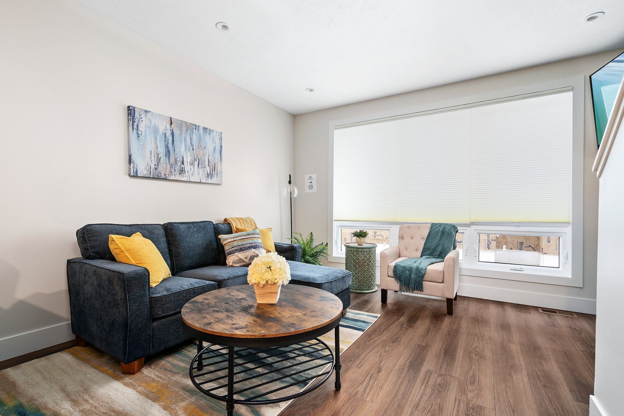 A modern living room with a sectional sofa, a round coffee table, and a view of the city through large windows.