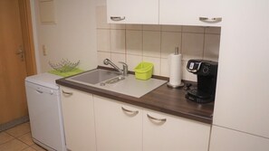 Une cuisine compacte équipée d’un évier, d’une machine à café et d’un égouttoir à vaisselle.
