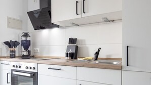 Eine moderne Küche mit weißen Schränken, einem eingebauten Backofen, einer Kaffeemaschine und einer Dunstabzugshaube.