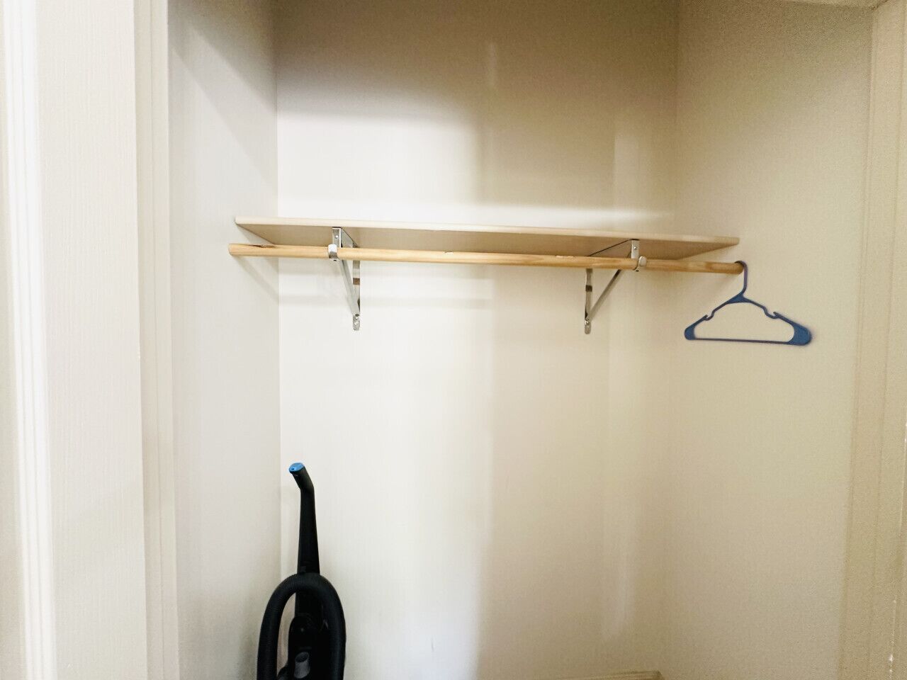 Een kast met een houten plank en een blauwe kleerhanger.
