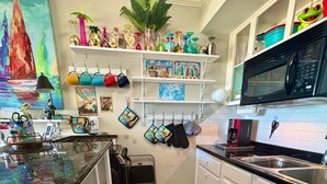 Uma cozinha compacta com armários brancos, micro-ondas, pia e tapete preto.