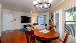 A dining area with a wooden table and chairs, a flat-screen TV mounted on the wall, a ceiling fan, and a window with blinds. - 2 King Suites with Heated Pools/Spas/Gym in great North Scottsdale Location! (Scottsdale)