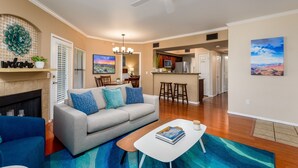 A living room with a gray sofa, blue cushions, a coffee table, and a fireplace. - Villa Acacia 2 Bedroom Condo by RedAwning (Scottsdale)
