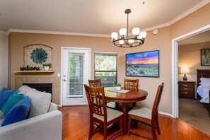 A dining area with a wooden table and chairs, a chandelier, a fireplace, and a 'welcome' sign above it.