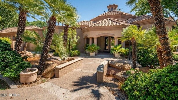 A Mediterranean-style villa with a tiled roof, palm trees, and a stone pathway leading to the entrance. - Villa Acacia 2 Bedroom Condo by RedAwning (Scottsdale)