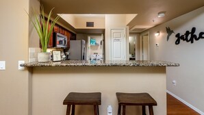 A kitchen with granite countertops, wooden cabinets, a potted plant, and a 'Penny' sign on the door. - Villa Acacia 2 Bedroom Condo by RedAwning (Scottsdale)