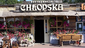 Ein rustikales Restaurant mit einem Reetdach, Holzschildern und farbenfrohen Blumenarrangements.