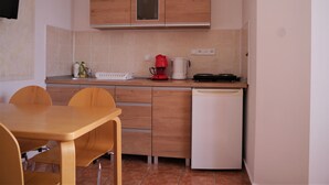 Eine kleine Küche mit Holdekor-Schränken, einer weißen Arbeitsplatte, einer Kaffeemaschine und einem Geschirrspüler.