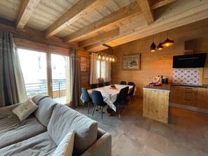 A cozy cabin interior with a dining area, kitchen, and a sofa.