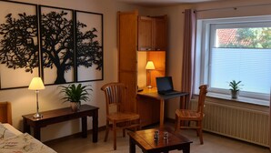 A cozy room with a bed, a desk with a laptop, two chairs, a small table, a lamp, and a window with curtains. - 5-star vacation apartment "Hedfan" in Cnauceltaidd (Halle)