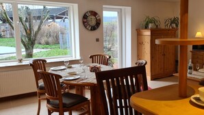 A dining area with a wooden table set for four, a clock on the wall, and a view of the outdoors. - 5-star vacation apartment "Hedfan" in Cnauceltaidd (Halle)