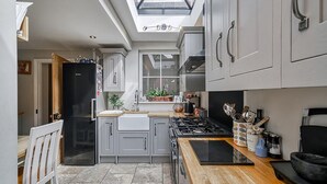 A modern kitchen with grey cabinets, a black refrigerator, a wooden countertop, and a skylight above the sink.