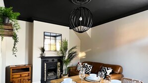 A dining area with a wooden table set for four, a fireplace, and a hanging plant.