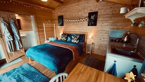 Una stanza accogliente in stile baita, con un letto, un angolo cottura e un soffitto in legno.